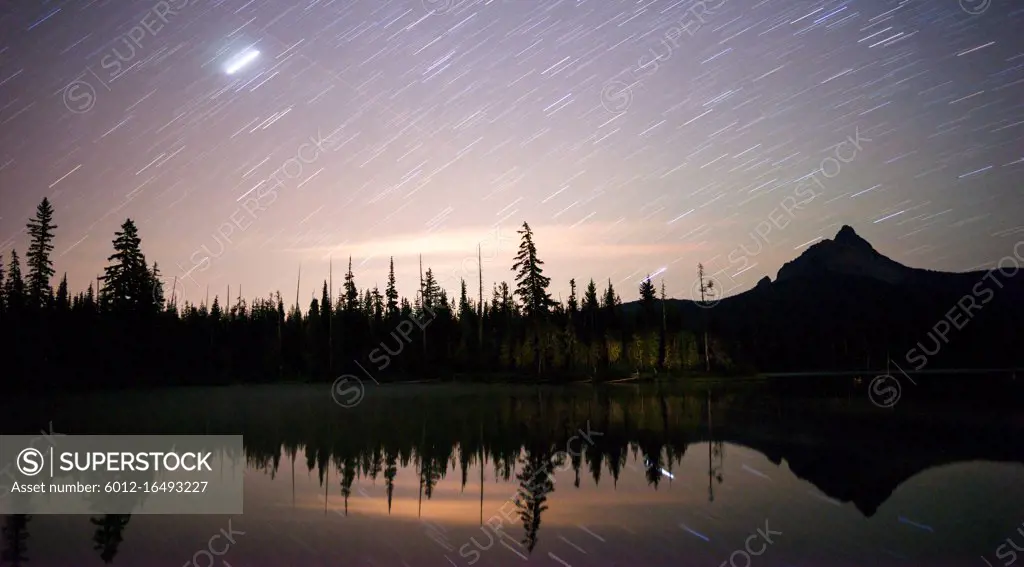 A long exposure over water of the night sky in the mountains