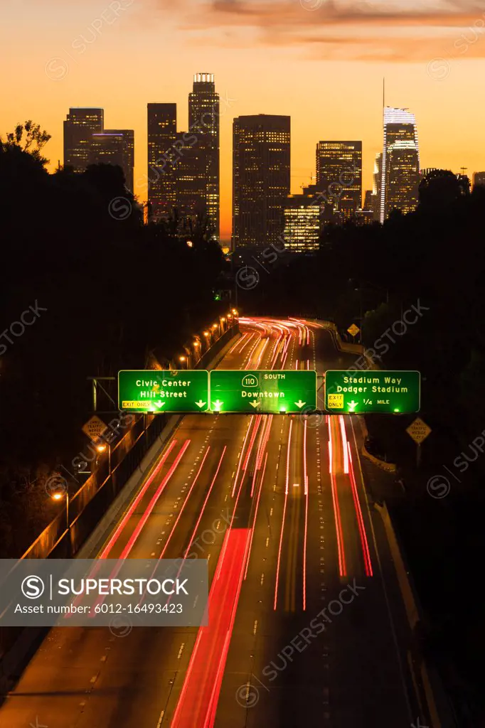 Light streaks from brake lamps flow across the foreground ad sunset falls on Los Angeles