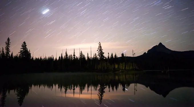 A long exposure over water of the night sky in the mountains