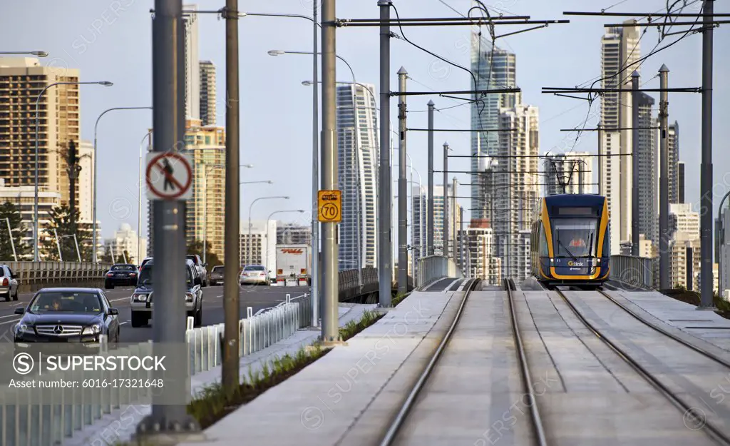 Tram travelling alongside road and Surfers Paradise city in the background