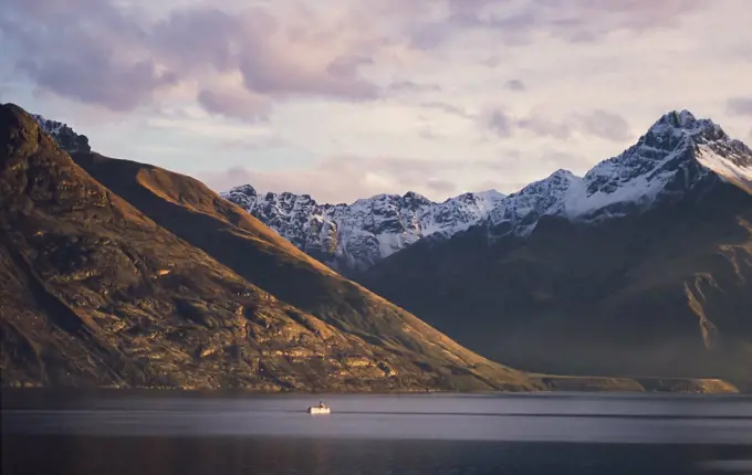 Steam boat on Lake Wakatipu and snow capped mountain range behind - New Zealand