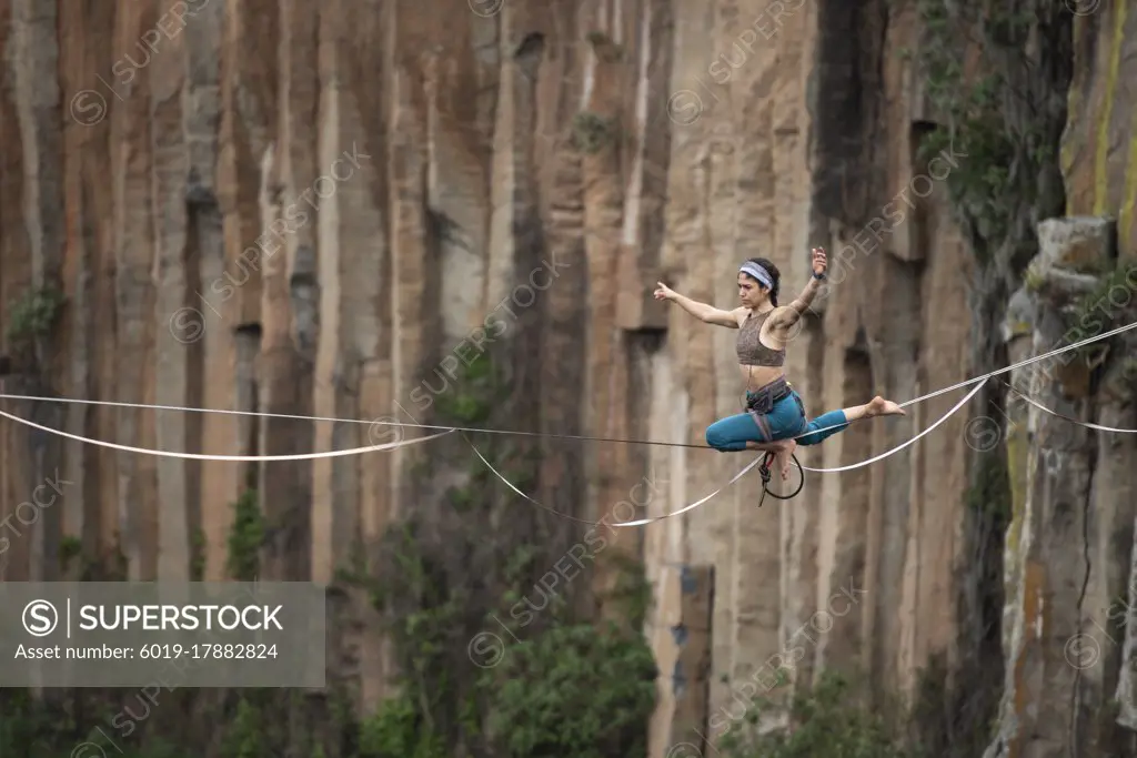 One girl performs acro yoga balancing on a highline at El Gato canyon