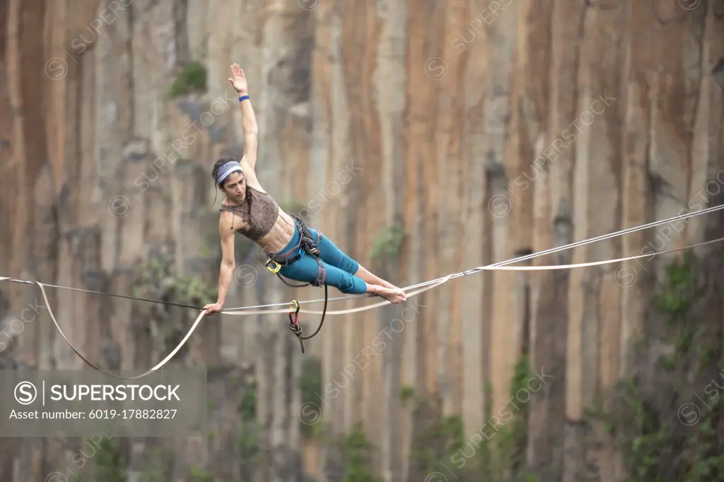 One girl performs acro yoga balancing on a highline at El Gato canyon