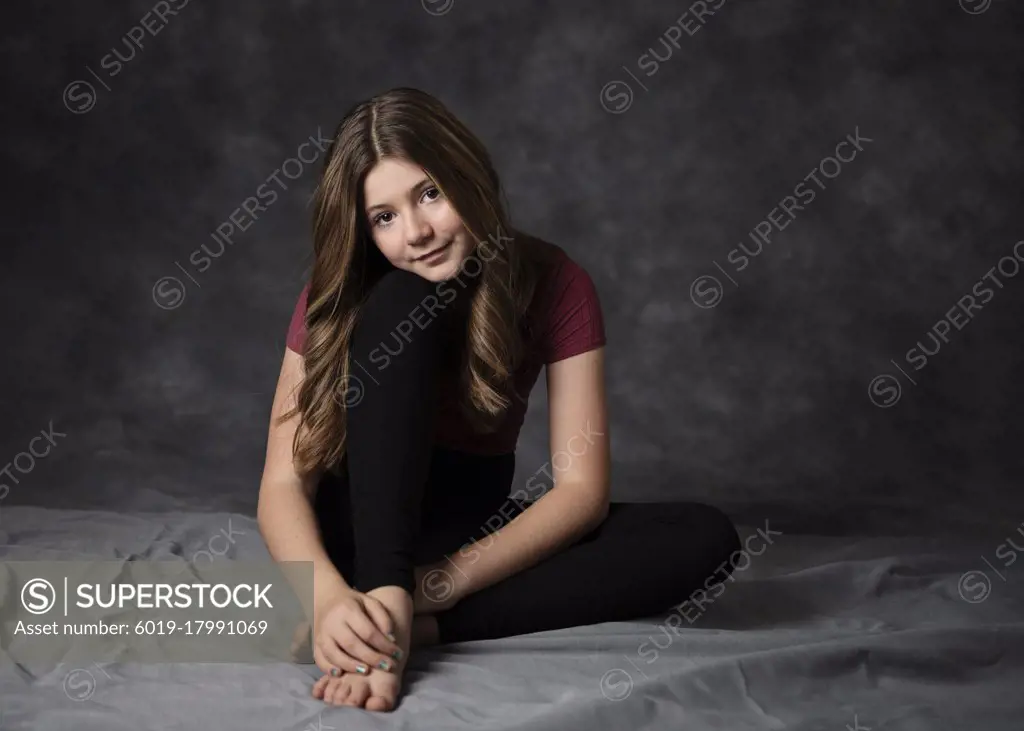 Beautiful tween girl sitting on floor, low key.