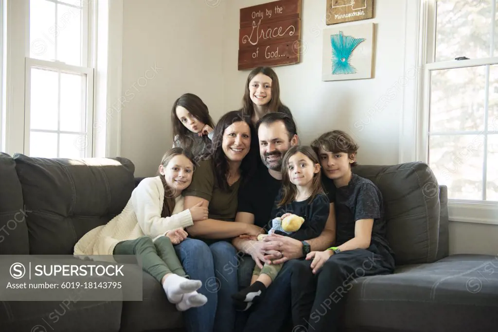 Beautiful family of seven sitting on the couch in their living room.