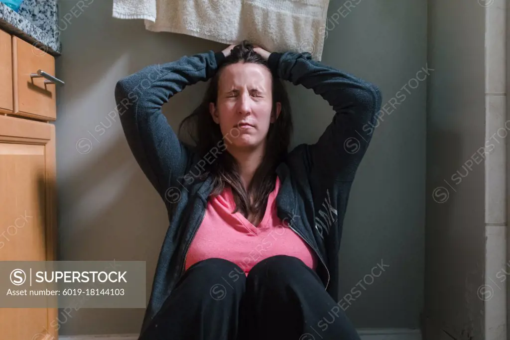 Young woman holding head closing eyes in domestic bathroom, headache