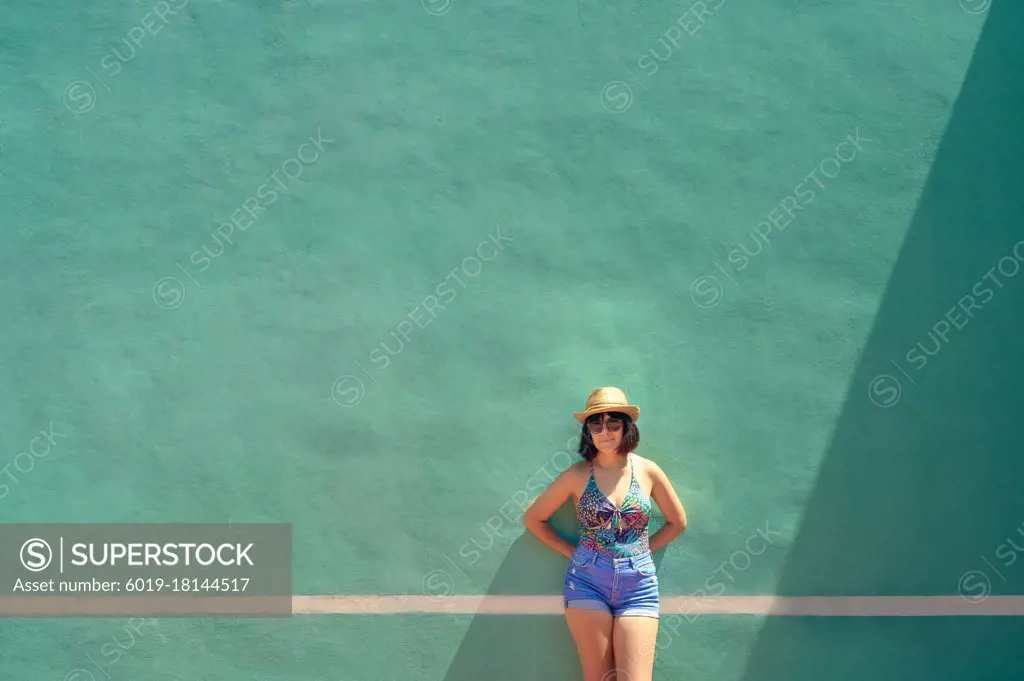 Portrait of a pretty young woman front of a training wall on a tennis