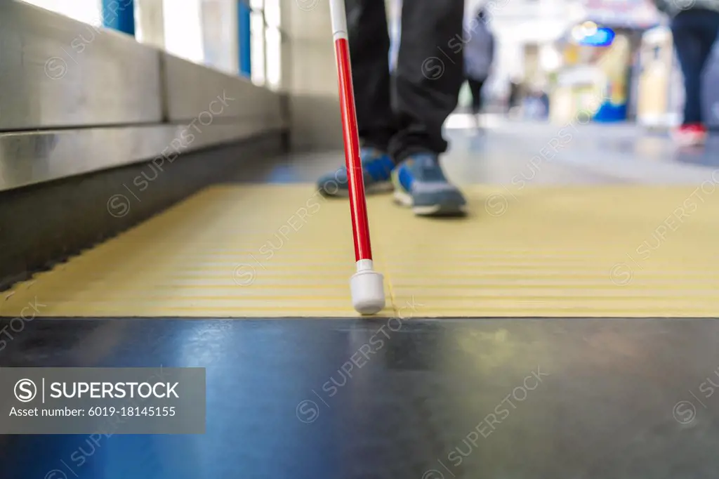 blind person using his cane to guide himself down the street