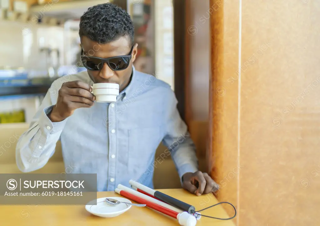 young blind african man having a coffee