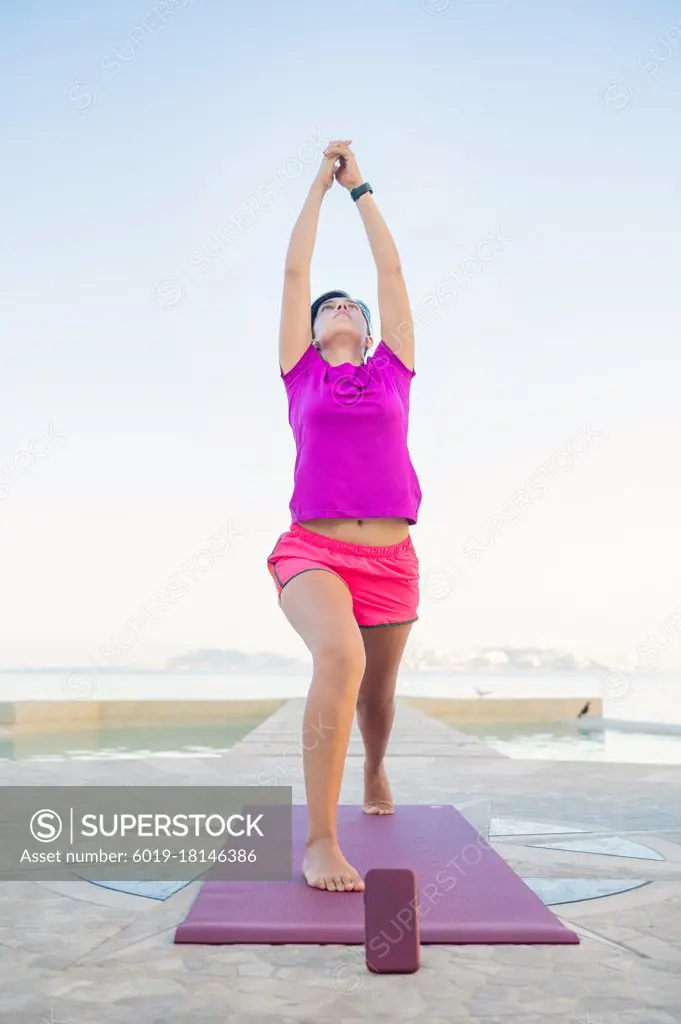 Woman practices yoga in front of the pool. Yoga poses outdoors