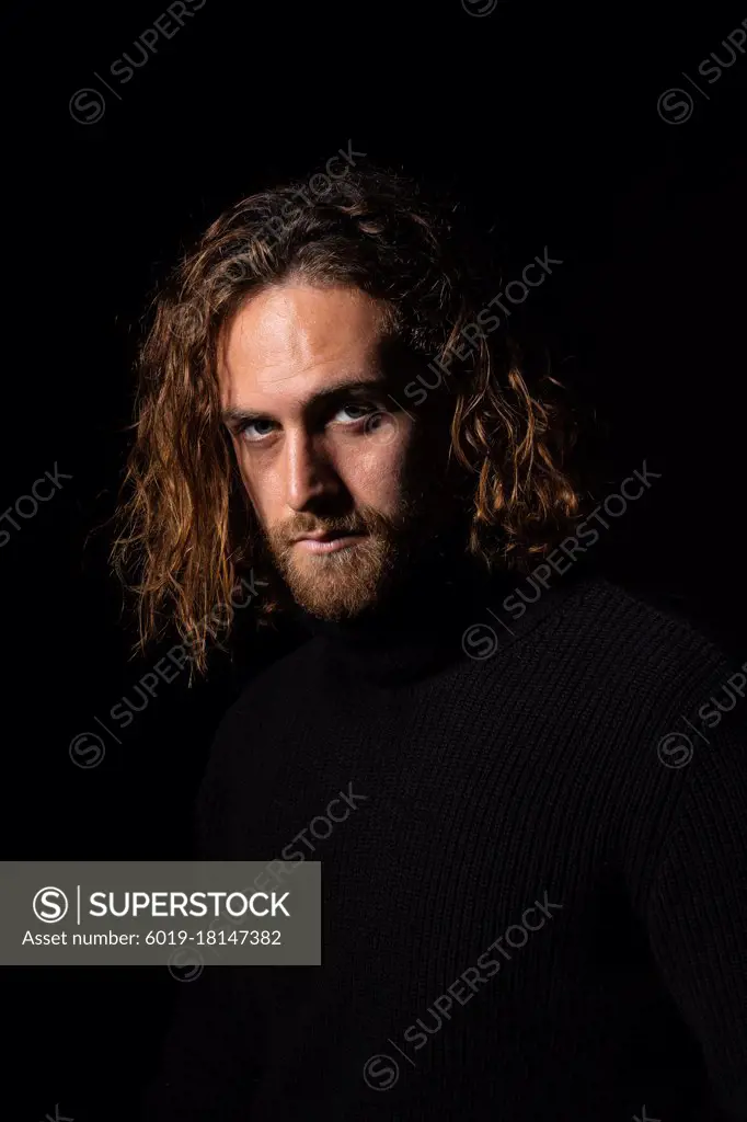 attractive man with long hair and blue eyes looking to camera indoor