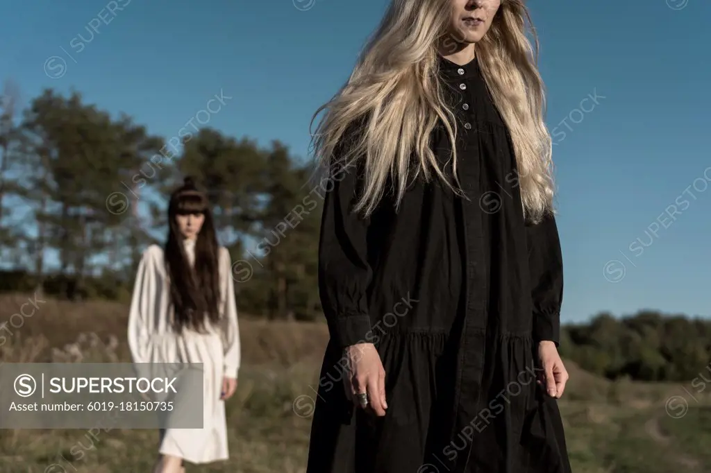 two beautiful twin girls doing style lying in a field at sunset