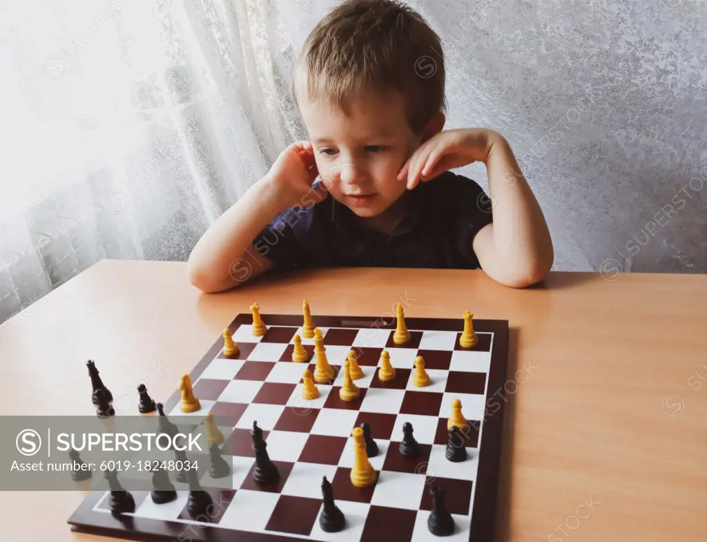 little boy thinks while playing chess at home. leisure