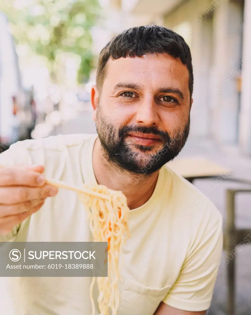 Latino boy in yellow t-shirt eating japanese food