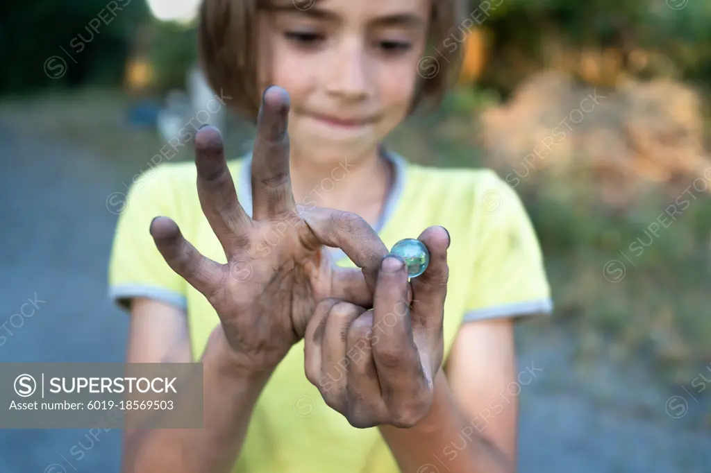 Young boy holding murbel tay in his dirty hands