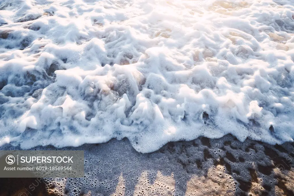 close-up of waves with sea foam against sunset