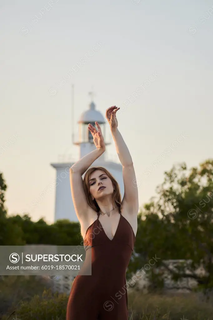 Young woman poses in a maroon dress at the Santa Pola Lighthouse