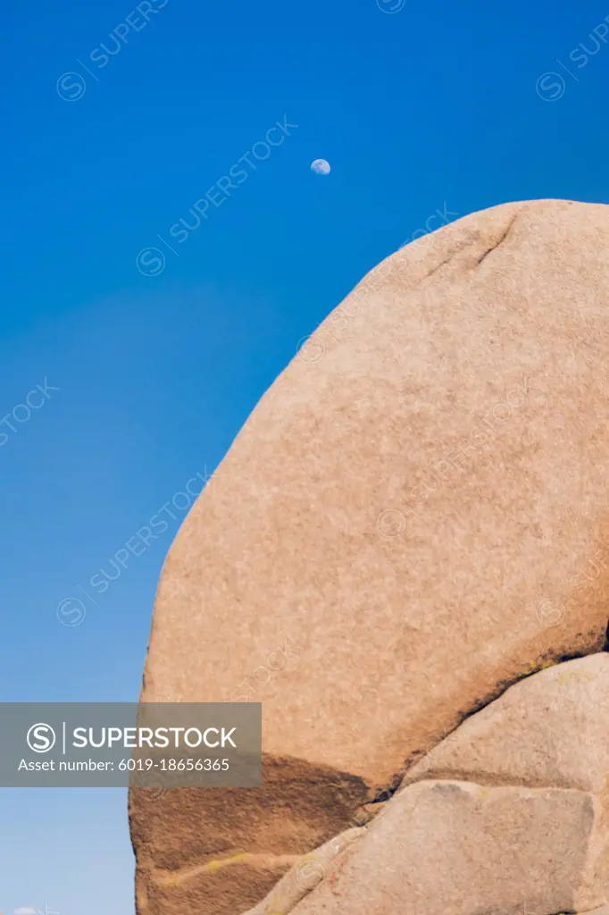 Moon seen during the day on a blue sky in the desert.