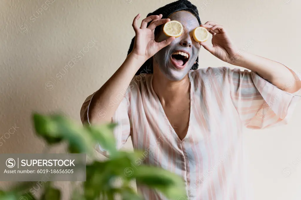 Happy girl applying a facial cleansing mask while