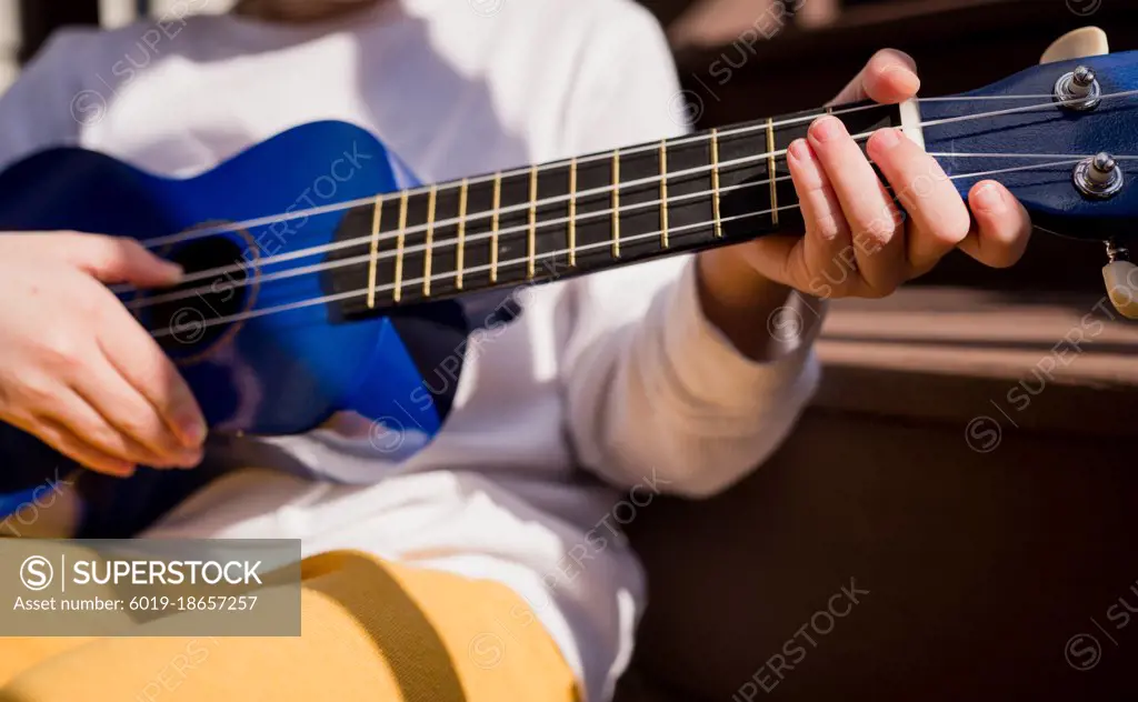 Small boy playing the ukulele in the sunshine