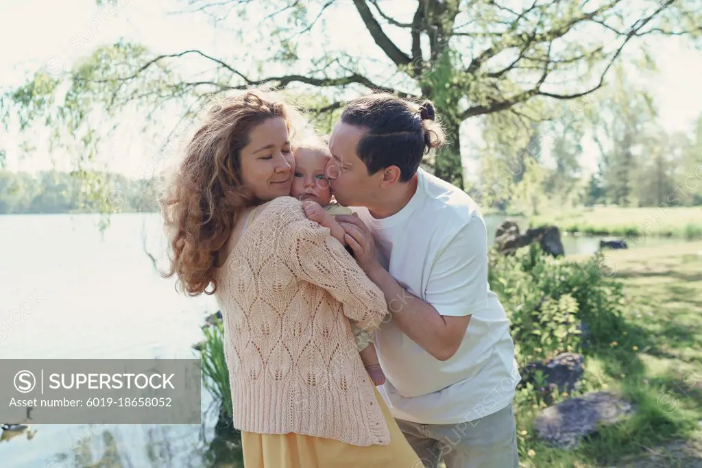 Two parents holding a son in the park