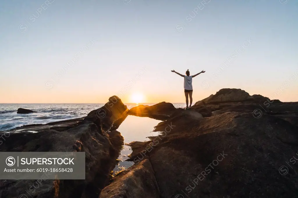 a person standing in a sea landscape against sunset