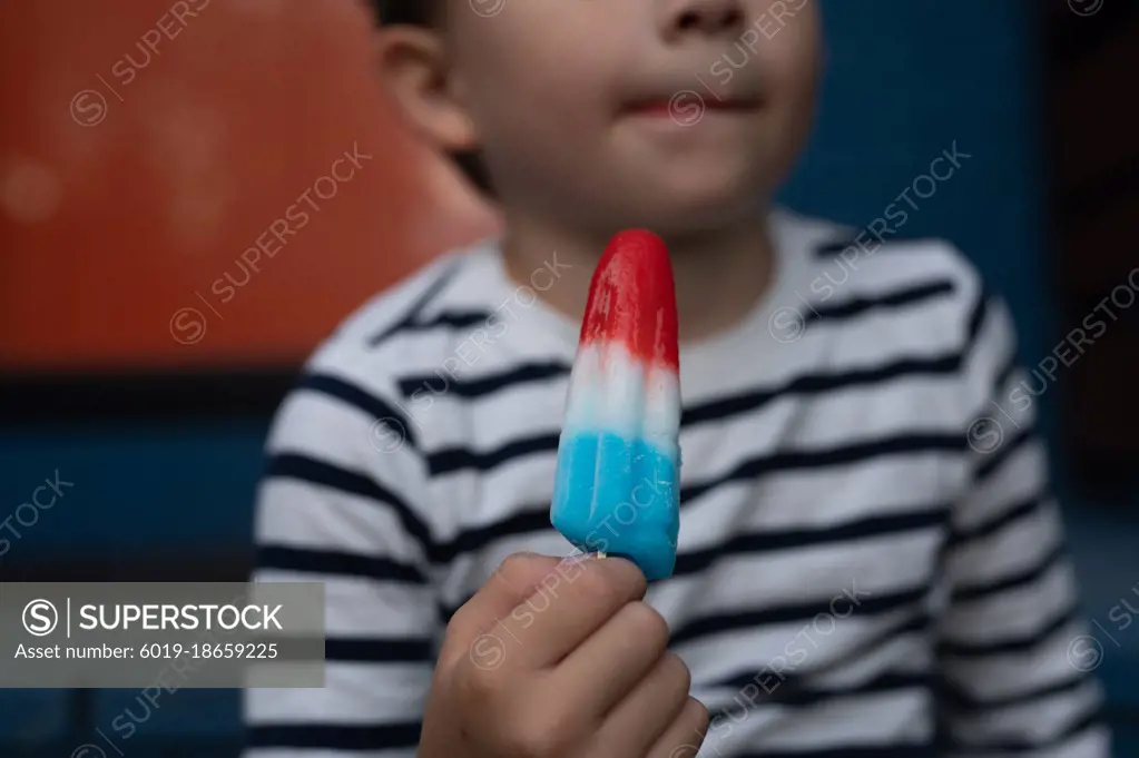 Young boy with melting popsicle on front porch