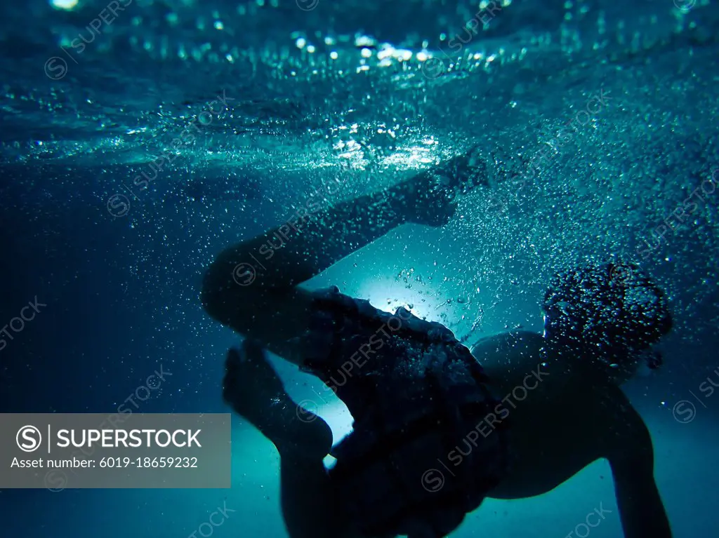 Dreamy underwater shot of child in dark swimming pool