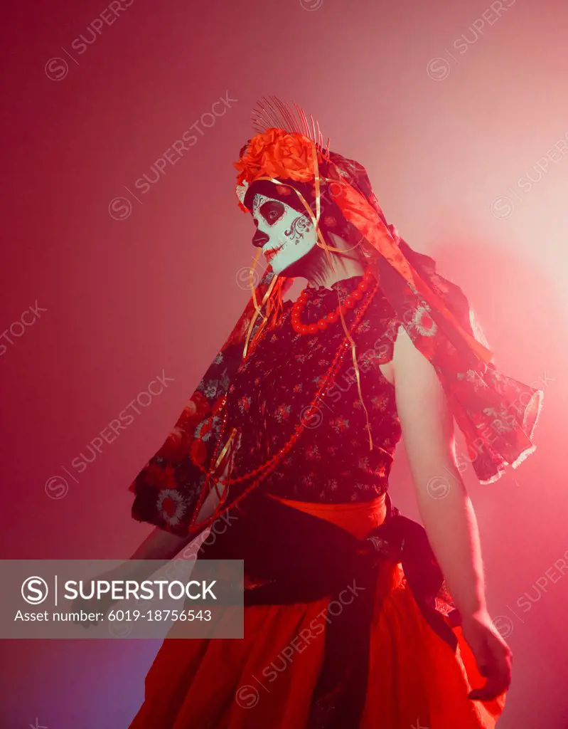 Young woman in calavera style with Mexican skull make-up on her face