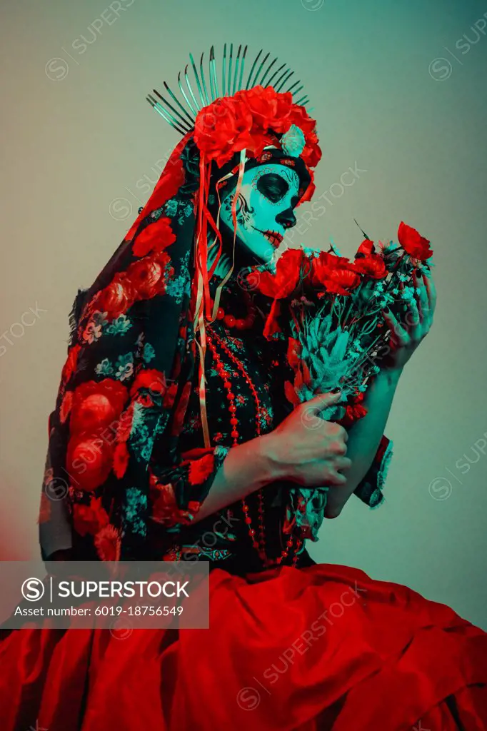 Young woman in calavera style with Mexican skull make-up on her face