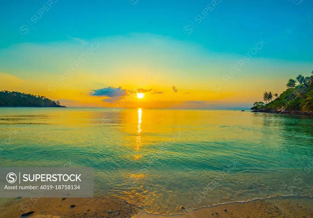 Coconut palms on sand beach in tropic on sunset. Thailand