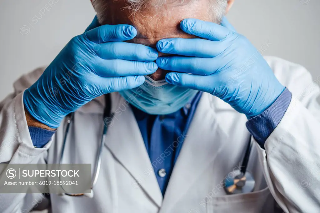 Doctor desperate for rest holding his hands on his head