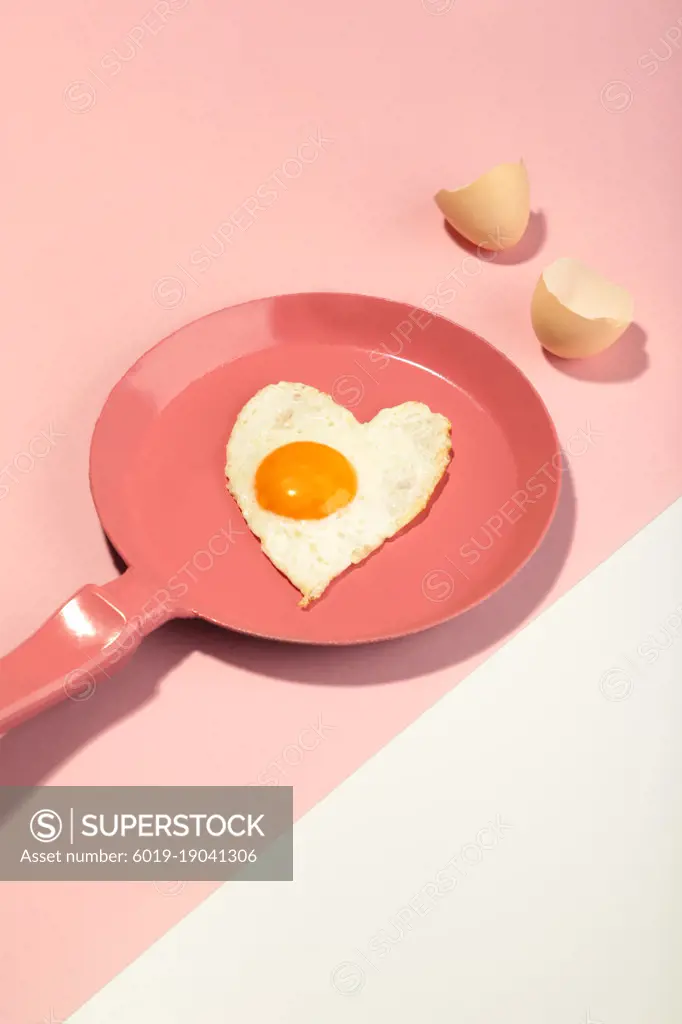 Pink frying pan and egg in heart shape. Valentine's day