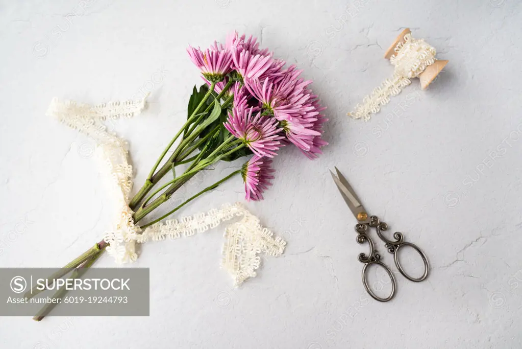 Pink flower flat lay, with scissors and lace on wooden spool