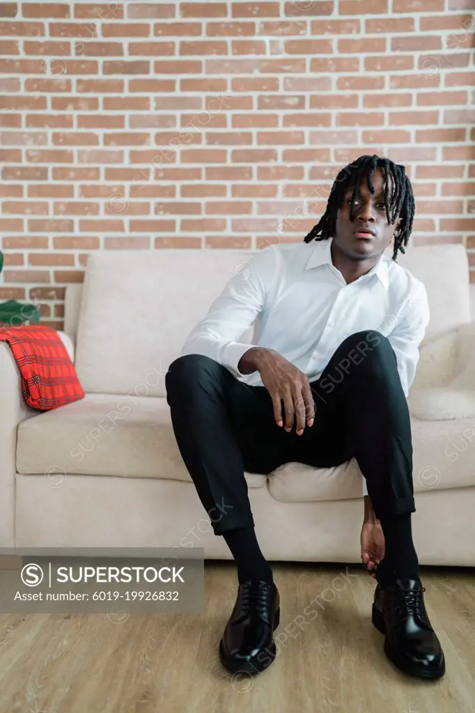 Portrait of the black man with dreadlocks wearing a suit sitting