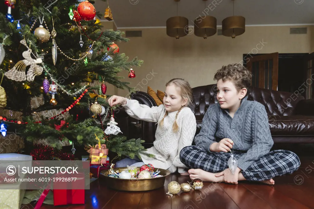 Children decorate the Christmas tree with Christmas toys.