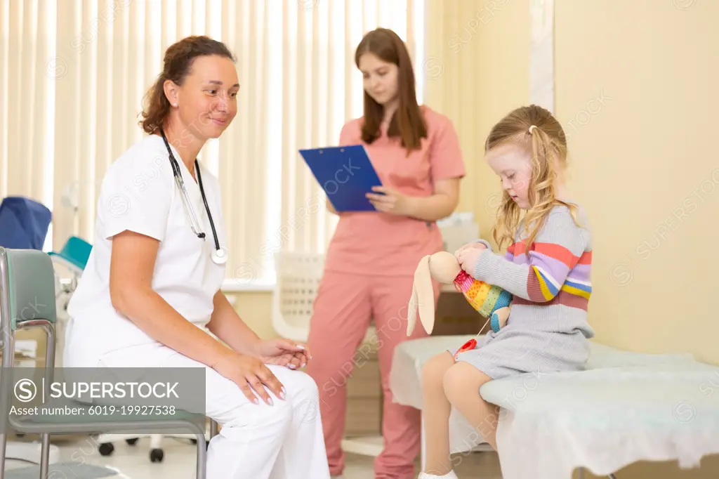 Doctor and nurse chatting with little girl in doctor's office