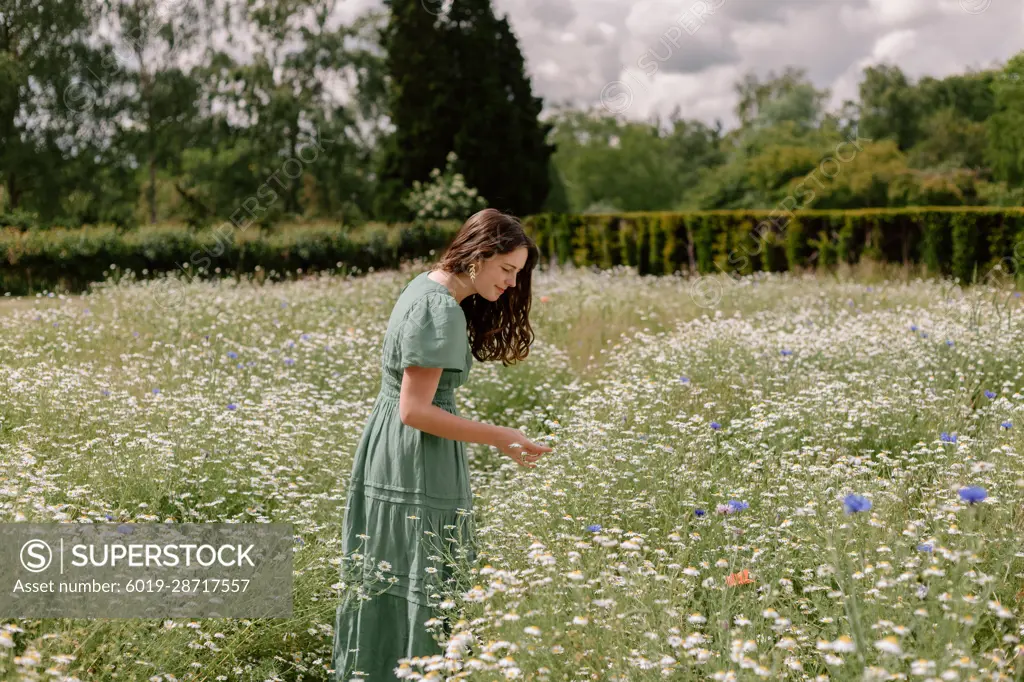 Woman in green dress in wild flower field - SuperStock