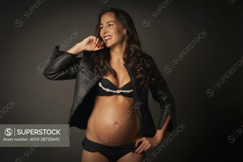 Pregnant woman posing smiling in underwear and leather jacket