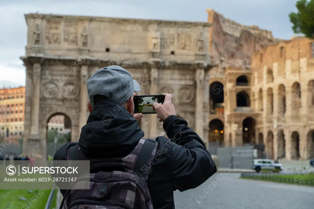 tourist man taking picture with his mobile phone at coliseum