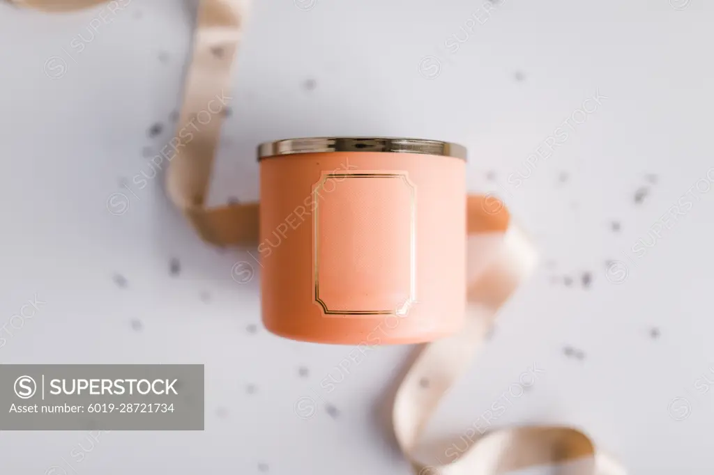 Peach colored candle in focus with ribbon and sprinkles