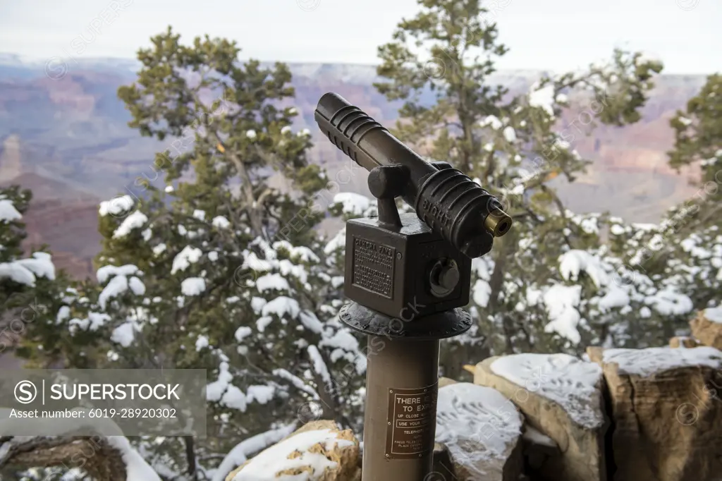 Coin-operated telescope, snow covered pine trees at the Grand Canyon