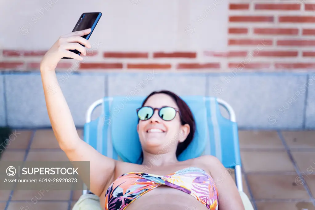 attractive young woman taking a selfie with her smartphone on vacation