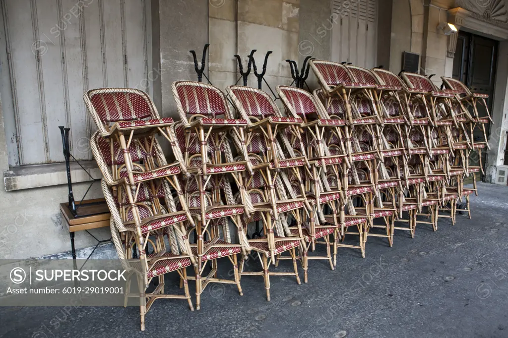 Cafe chairs stacked on a sidewalk in Paris, France.