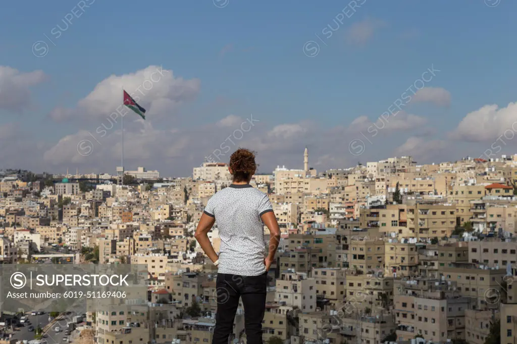 Male tourist looking at Amman's cityscape during sunny day