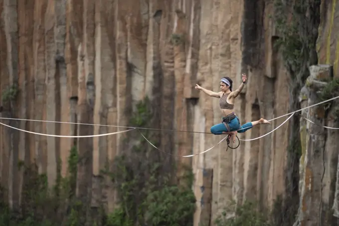 One girl performs acro yoga balancing on a highline at El Gato canyon