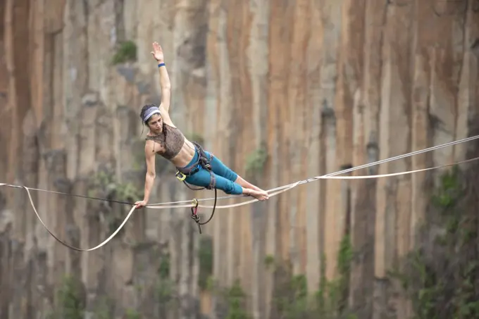 One girl performs acro yoga balancing on a highline at El Gato canyon