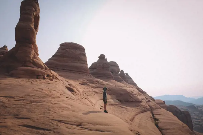 Young Boy Stands on a Cliff Edge Facing the Desert