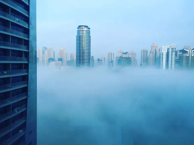 Modern skyscrapers of Dubai Marina in blue fog, climate change