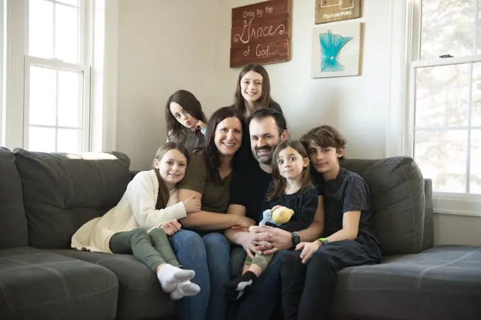 Beautiful family of seven sitting on the couch in their living room.